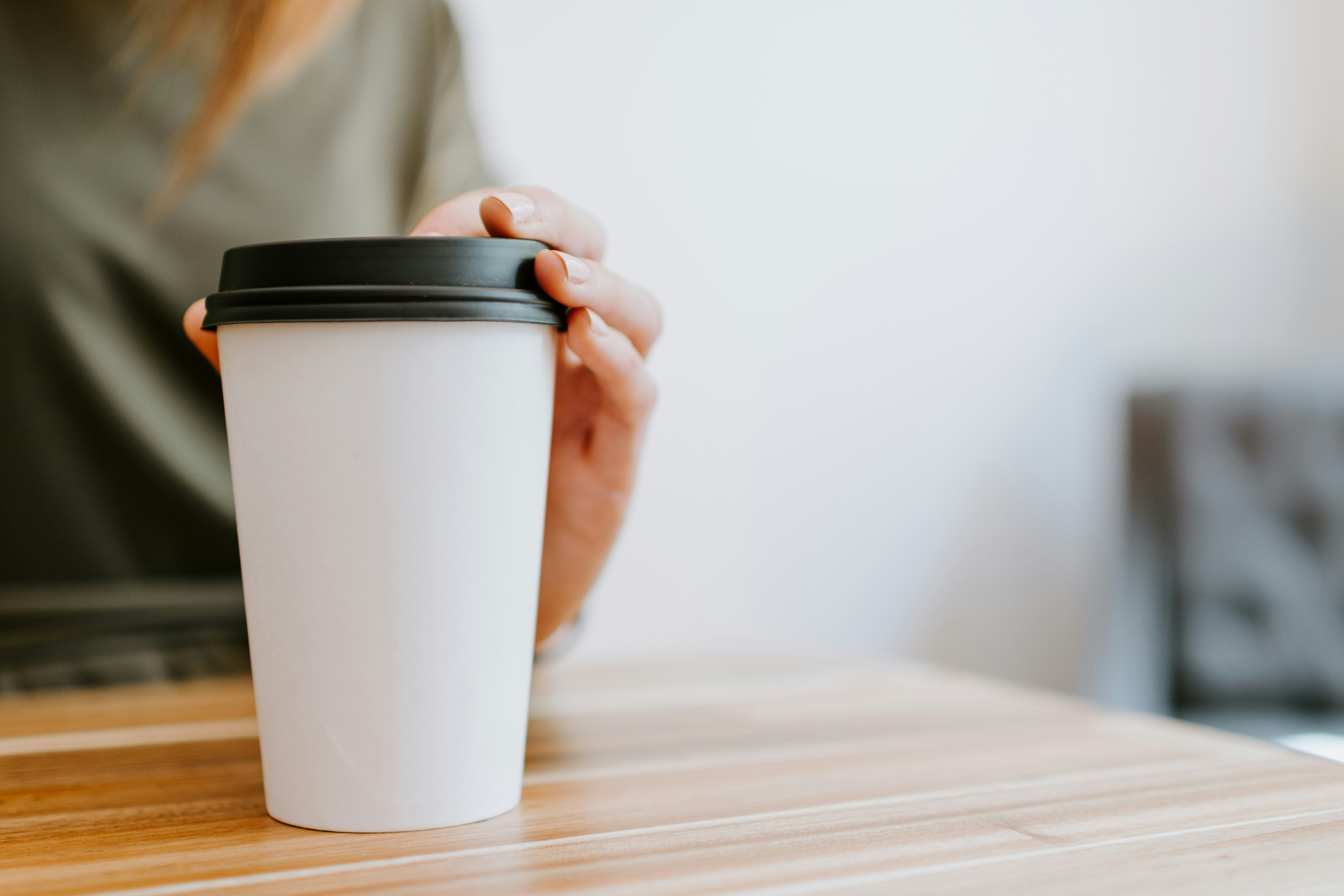 person holding white disposable cup